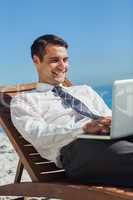 Young businessman on a deck chair using his computer