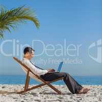 Young businessman on his beach chair using his laptop