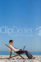 Young businessman on his deck chair using his laptop