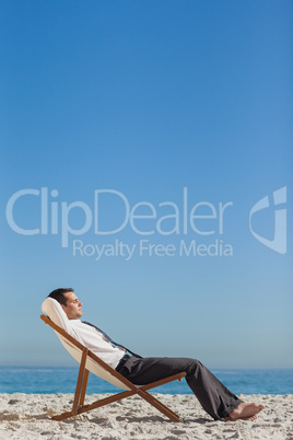 Young businessman relaxing and tanning on his deck chair