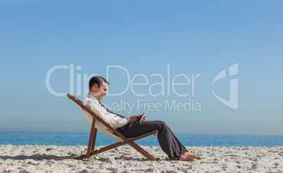 Young businessman resting on his deck chair using his tablet