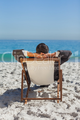 Relaxed young businessman resting on his sun lounger