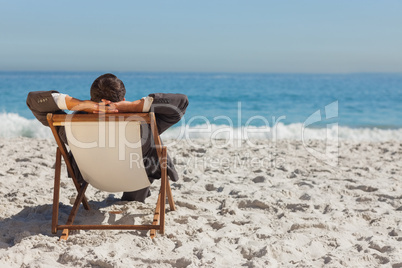 Young businessman relaxing on his sun lounger