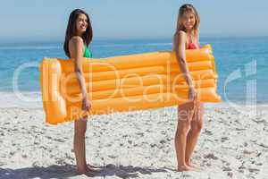 Two pretty friends holding air mattress