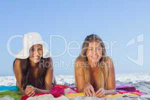 Two smiling friends lying on the sand