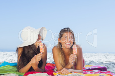 Smiling pretty women lying on their beach towel