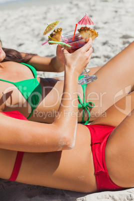 Sexy women taking sun clinking glasses of cocktail