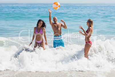 Happy friends playing with a beachball in the sea