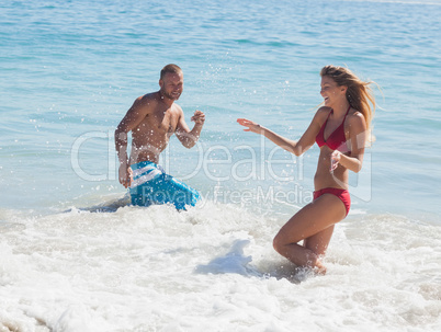 Cheerful friends throwing water to each other in the sea