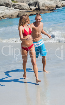 Cheerful couple in swimsuit walking together