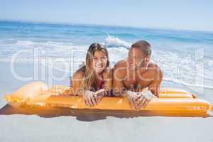 Cheerful cute couple in swimsuit lying on the beach