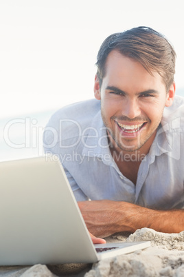 Happy handsome man on the beach with his laptop