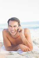 Smiling handsome man on the beach having a phone call