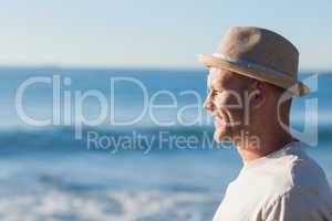 Handsome man wearing straw hat looking at the sea