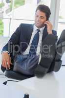 Businessman on the phone relaxing with his feet on his desk