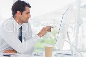 Concentrated businessman analyzing documents on his computer scr