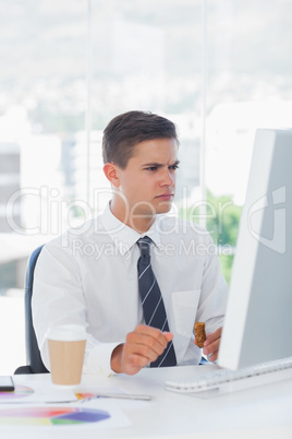 Young businessman frowning while looking at computer