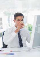 Young businessman drinking coffee at his desk