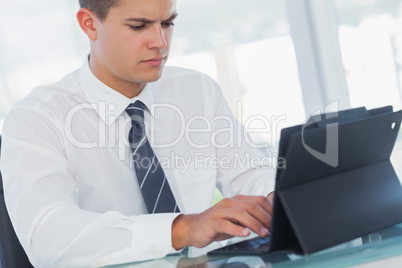 Serious young businessman working on his tablet pc