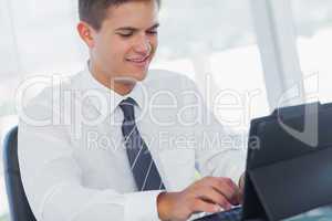 Cheerful young businessman working on his tablet pc