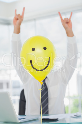 Yellow balloon with cheerful face hiding rock and roll businessm