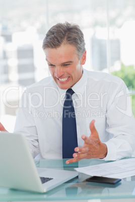 Angry businessman looking at his laptop