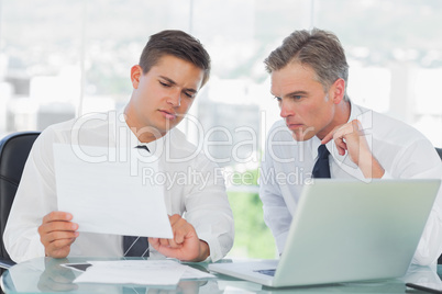 Concentrated businessman listening to his intern while explainin