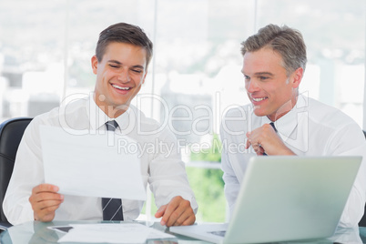 Smiling businessman listening to his intern while explaining doc