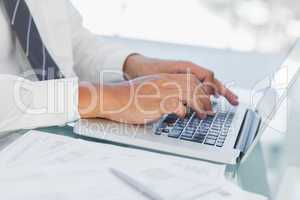 Close up on businessmans hands typing on his laptop