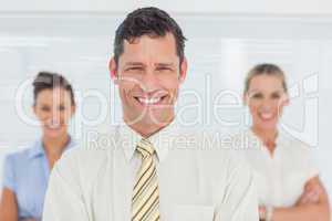 Smiling businessman posing with his colleagues on background