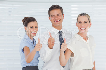 Cheerful colleagues posing with thumbs up