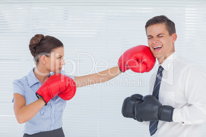 Businesswoman punching her colleague while boxing together