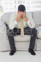 Troubled businessman sitting on sofa