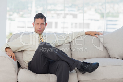 Serious businessman posing sitting on sofa