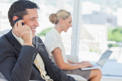 Businessman on the phone with his colleague working on computer