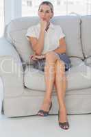 Thoughtful attractive businesswoman posing sitting on sofa