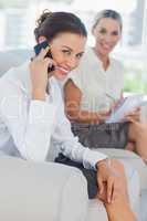 Businesswoman having a phone call while her colleague writing