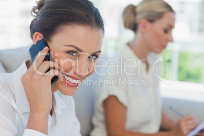 Businesswoman having a call while her colleague writing