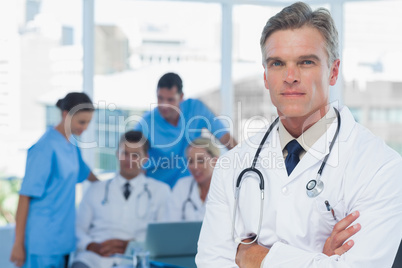 Experienced doctor posing with colleagues in background