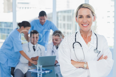 Smiling blond doctor posing with colleagues in background