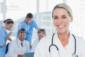 Cheerful blond doctor posing with colleagues in background