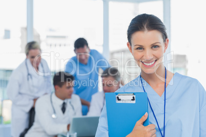 Cheerful young surgeon posing with colleagues in background