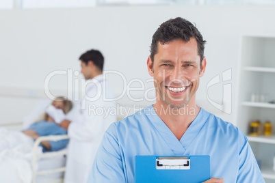 Portrait of surgeon with doctor attending patient on background