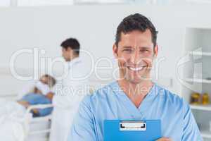 Portrait of surgeon with doctor attending patient on background