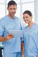 Smiling surgeons working together on tablet