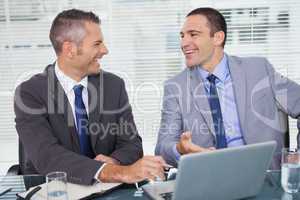 Cheerful businessmen laughing while working
