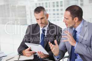 Serious businessmen analyzing documents on their tablet
