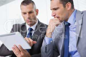 Focused businessmen analyzing documents on their tablet