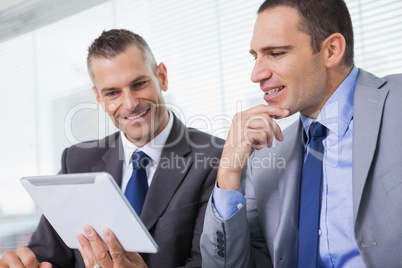 Smiling businessmen working together on their tablet