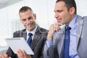 Smiling businessmen working together on their tablet